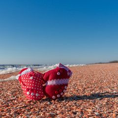 Image of soft toys in the form of mittens on the beach. Handwork.