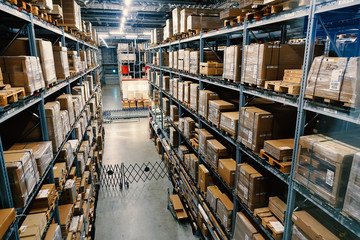 Large wharehouse with rows of shelves and goods boxes.