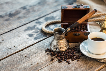 coffee cup, metal turk and coffee beans on a wooden background