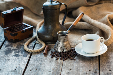 coffee cup, metal turk and coffee beans on a wooden background