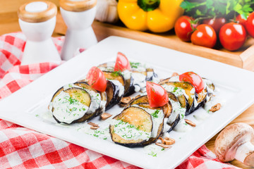 Grilled slices of eggplant and tomatoes in stack with spicy sauce