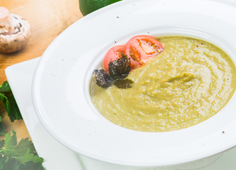 bowl of broccoli and green peas cream soup on wooden table