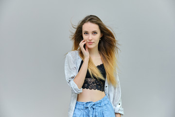 Photograph of a portrait of a beautiful girl woman with long dark flowing hair, satisfied life on a gray background. She stands in front of the camera in different poses with different emotions.