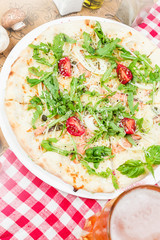 Homemade italian pizza, fresh cherry tomatoes and basil, arugula served on wooden board
