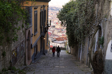 Panoramic staircase in Naples and two people descending between houses.