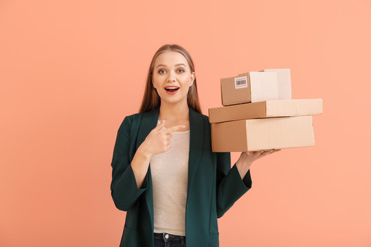 Happy woman with cardboard boxes on color background