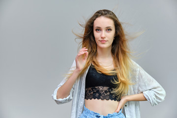 Photograph of a portrait of a beautiful girl woman with long dark flowing hair, satisfied life on a gray background. She stands in front of the camera in different poses with different emotions.