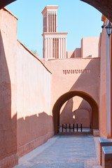 High narrow street of old adobe town with famous wind towers - Yazd, Iran
