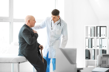 Naklejka na ściany i meble Doctor examining senior man in nursing home