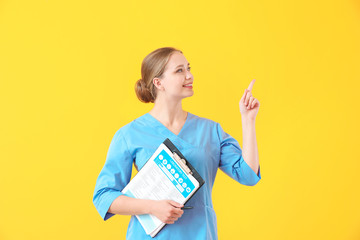 Young medical assistant with documents pointing at something on color background