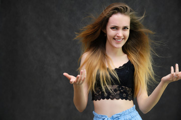 Photograph of a portrait of a beautiful girl woman with long dark flowing hair, happy life on a dark gray background. She is standing directly in front of the camera in various poses and smiling.