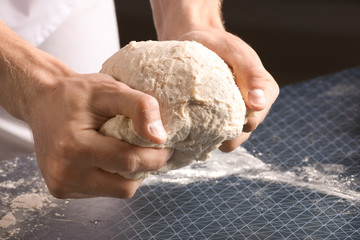 Man kneading dough in kitchen, closeup