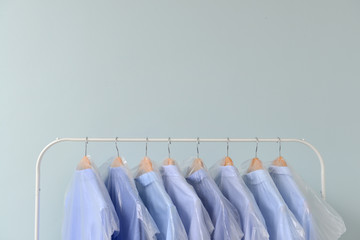 Rack with clothes after dry-cleaning on light background