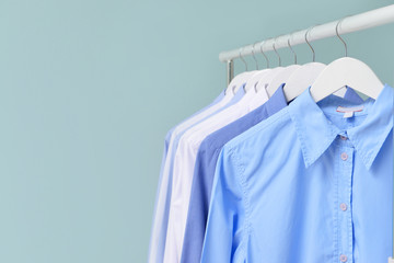 Rack with clothes after dry-cleaning on light background