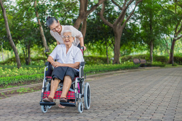 Fototapeta na wymiar Happy senior daughter and her mother in wheelchair are smiling and laughing in garden. They are Asian peoples in Thailand.