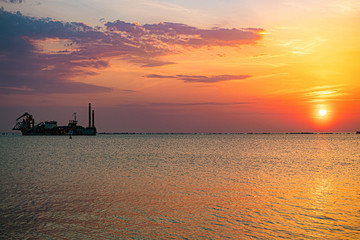 Beautiful sunset on the sea. Silhouette of a building ship.