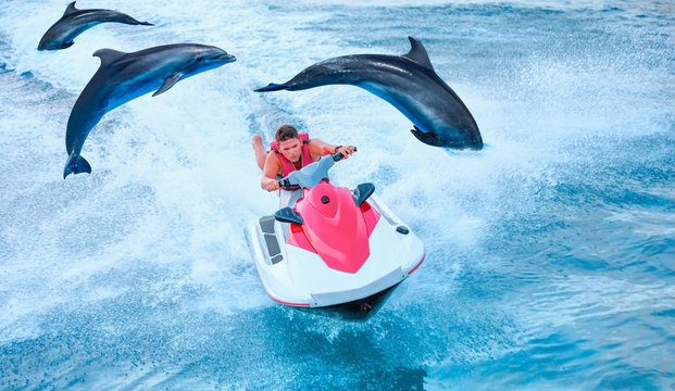 Man On Jet Ski Jump On The Wave With Jumping Dolphin In The Sea