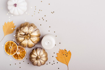 Fototapeta na wymiar Autumn Celebration concept. Decorative pumpkins, golden confetti and dry leaves on gray background