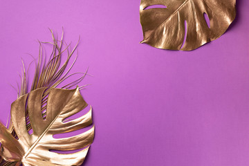 Golden tropical monstera leaf on violet background with copy space. Top view. Flat lay. Creative layout. Exotic summer concept in minimal style