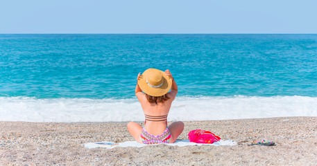 Lonely young girl sitting on beach looking at the sea - Alanya, Turkey