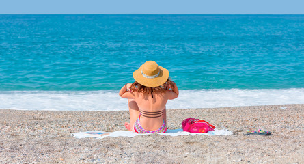 Lonely young girl sitting on beach looking at the sea - Alanya, Turkey