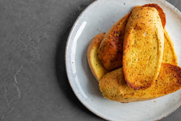 Garlic bread toasted and sliced on a plate,  with a grey tile background
