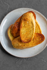 Garlic bread toasted and sliced on a plate,  with a grey tile background