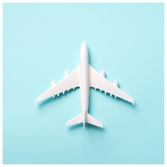 Travel, vacation concept. White model airplane on pastel blue color background with copy space. Top view. Flat lay. Minimal style design. Square crop