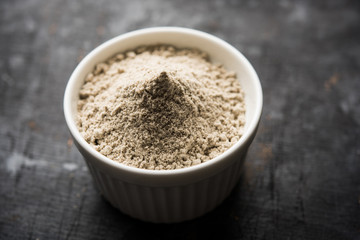 bajra  atta / flour of pearl millet served in a bowl with small wooden scoop, selective focus
