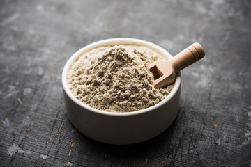 bajra  atta / flour of pearl millet served in a bowl with small wooden scoop, selective focus