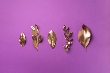 Golden leaves on violet background. Top view. Copy space. Summer and autumn concept. Creative design elements for invitation, wedding cards, valentines day, greeting cards.