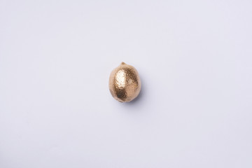 Golden lemon on grey background. Creative food concept. Top view. Flat lay. Single exotic gold fruit.