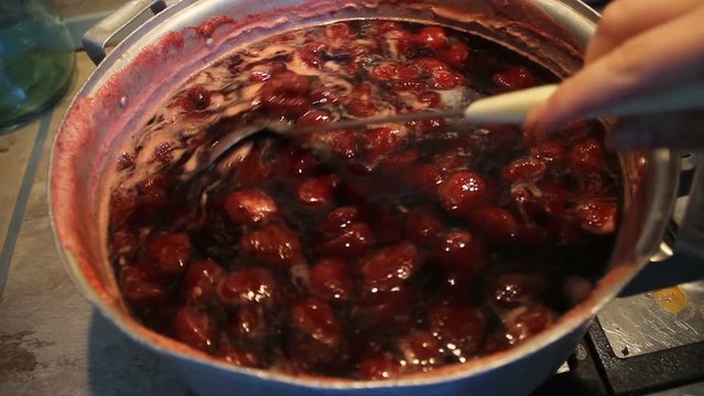 Preparation of strawberry jam. Cook jam. A woman's hand with a ladle neatly stirs the berry homemade jam. Traditional cuisine