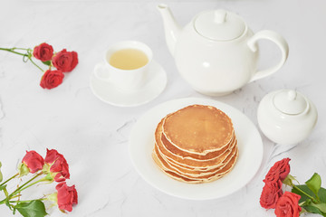 Independence Day on July 4th, American pancakes on the table next to the crockery and red roses.