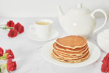 Independence Day on July 4th, American pancakes on the table next to the crockery and red roses.