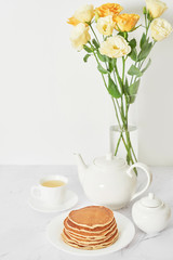 Independence Day on July 4th, American pancakes on the table next to the crockery and yellow flowers in the vase.