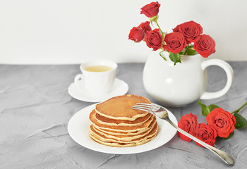 Independence Day on July 4th, American pancakes on the table next to the crockery and red roses.