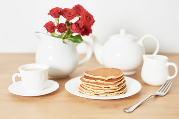 Independence Day on July 4th, American pancakes on the table next to the crockery and red roses.