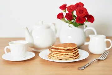 Independence Day on July 4th, American pancakes on the table next to the crockery and red roses.