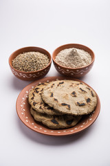 Bajra (pearl millet) / sorghum grains with it's flour or powder in a bowl, selective focus