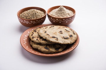 Bajra (pearl millet) / sorghum grains with it's flour or powder in a bowl, selective focus