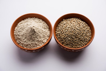Bajra (pearl millet) / sorghum grains with it's flour or powder in a bowl, selective focus