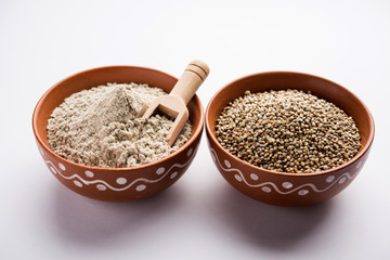 Bajra (pearl millet) / sorghum grains with it's flour or powder in a bowl, selective focus