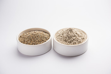 Bajra (pearl millet) / sorghum grains with it's flour or powder in a bowl, selective focus