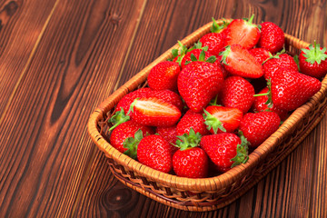 Juicy washed strawberries in wooden bowl on kitchen table.