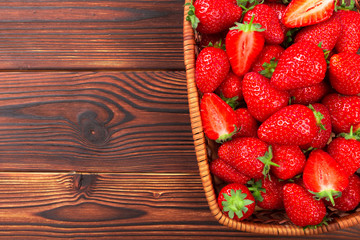 Juicy washed strawberries in wooden bowl on kitchen table.