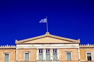 Fototapeta na wymiar The Greek flag waving at the top of the Greek Parliament in Athens, Greece