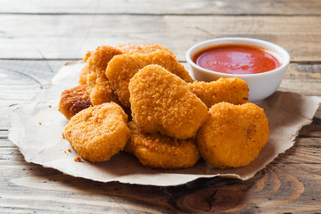 chicken nuggets with tomato sauce on wooden background. Copy space.