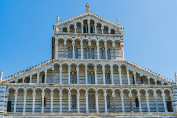Naklejka premium Details of the facade of the Medieval Roman Catholic Cathedral built in a Romanesque architectural style with multicolored marble, mosaic and high arches in the Piazza dei Miracoli, Pisa, Italy.