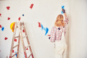 Working woman plastering / painting walls inside the house.
